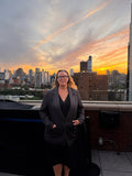 Woman standing on a rooftop with a city skyline and sunset in the background